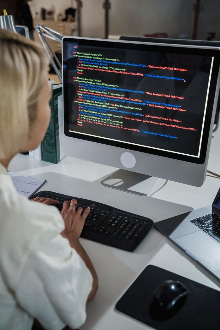 Crafting Captivating Headlines: Your awesome post title goes here A female programmer writing code on a desktop computer in an office setting with a focus on technology and IT development.